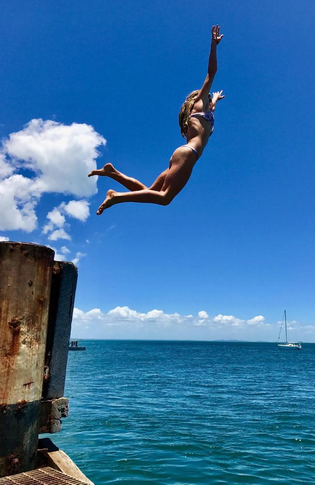 Grace Hayden jumps off a rock wall, which is holding back erosion at Amity on Straddie.