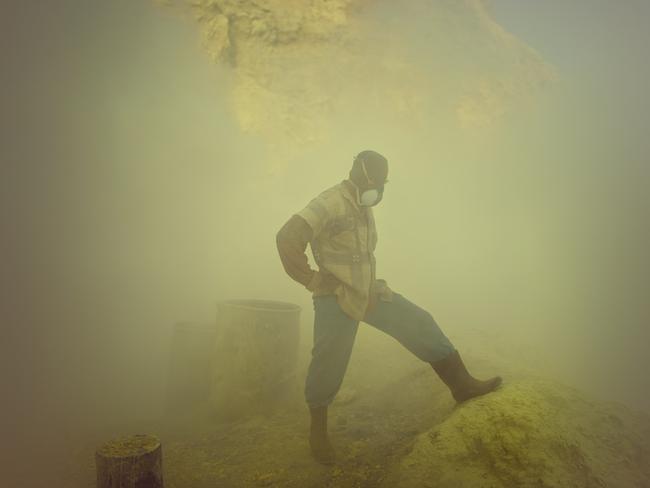 A worker pauses near the acid lake and is waiting for a clearer view and breath. Many workers have respiratory problems and have to cough even days after they left the volcano.