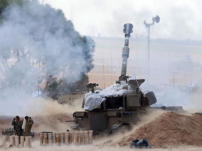 Israeli soldiers block their ears as a M109 155mm self-propelled howitzer fires rounds from near the Israeli border with Gaza in southern Israel. Picture: Menahem Kahana/AFP