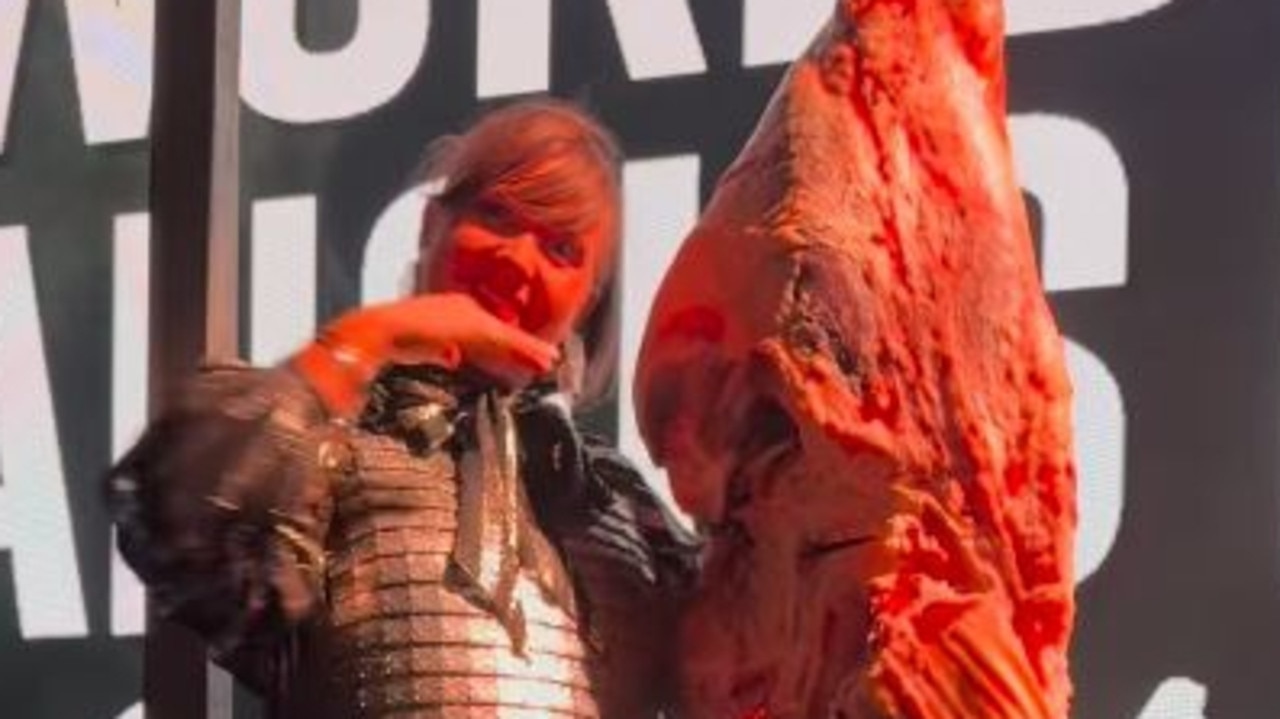 Rubber boots and knife with ballgown as ‘event butcher’ slices animal on stage