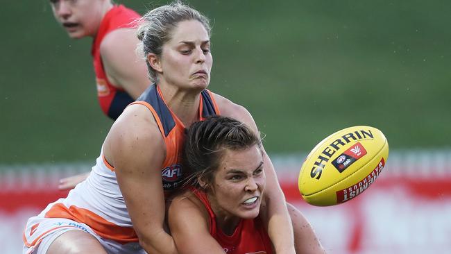 Melbourne's Madeleine Boyd handballs in front of Giants Ellie Brush during the women’s AFL. Brush is now returning to football.