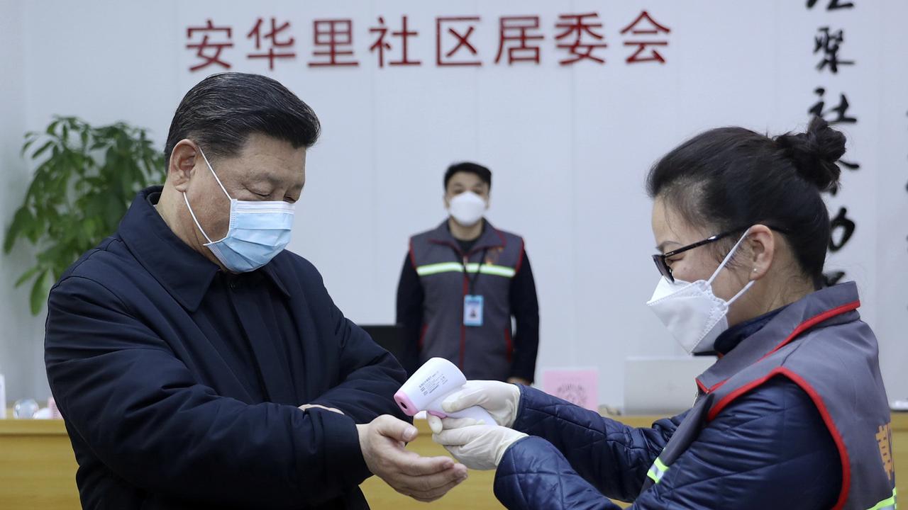 Chinese President Xi Jinping, left, wearing a protective face mask receives a temperature check as he inspects the coronavirus pneumonia prevention and control work at a neighbourhoods in Beijing. Picture: Pang Xinglei/Xinhua via AP