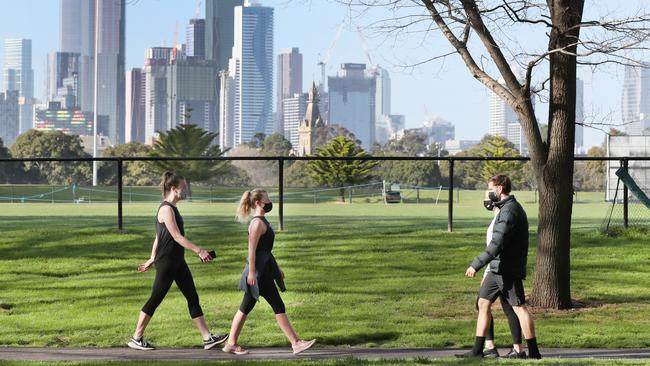 Walkers at Princess Park abiding by Melbourne’s mask rules. Picture: David Crosling