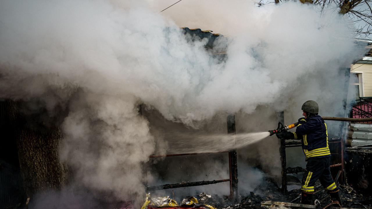 A rescuer extinguishes a fire in a burning shop after Russian shelling. (Photo by Dimitar DILKOFF / AFP)