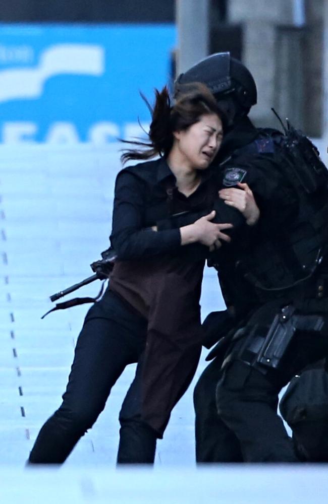 It was the image that for many defined one of the most shocking days in Sydney’s history. This Lindt Cafe worker could not race into the arms of the heavily armed policeman fast enough in her dash for freedom after being kept hostage by deranged gunman Man Horan Monis inside the Sydney CBD cafe. The photo of her in tears as she held onto the police officer was splashed across the front pages of leading newspapers in Britain and the US.