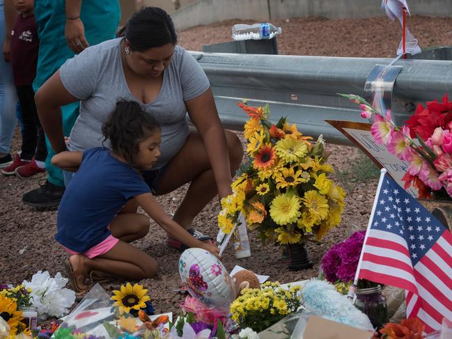 A family places flowers at a makeshift memorial outside the Cielo Vista Mall Wal-Mart (background) where a shooting left 20 people dead in El Paso. Picture: AFP