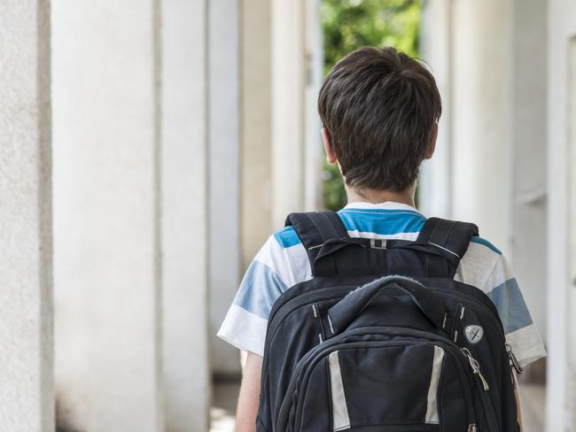 Teenage school boy with a backpack walking to school