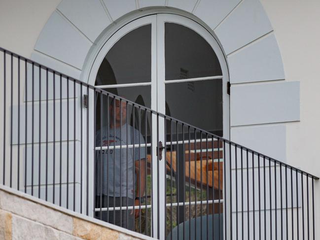 Rodney Rosmarin, husband of Optus CEO Kelly Bayer Rosmarin, peers from a window of their Vaucluse home on Thursday. Picture by Max Mason-Hubers