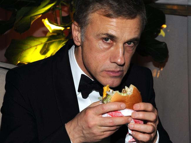 Celebs are just like us ... Christoph Waltz soaks up the champers with a burger.