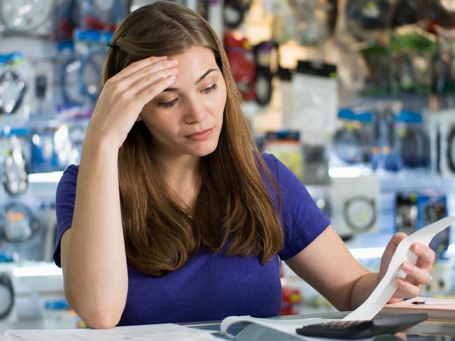 Young white female entrepreneur running a small business and working in computer shop, checking bills and invoices with worried expression istock image