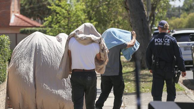 People leave one of the addresses during the police raids. Picture: Dylan Robinson