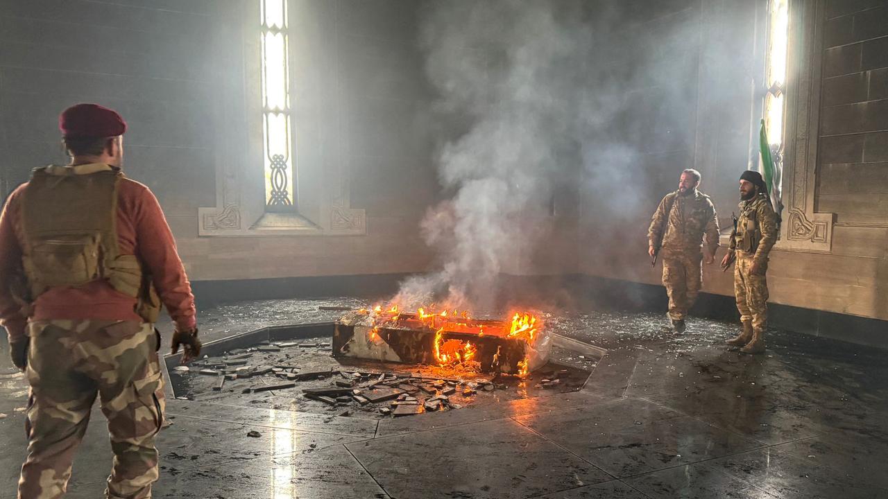 Rebel fighters stand next to the burning gravesite of Syria's late president Hafez al-Assad at his mausoleum. Picture: Aaref Watad/AFP