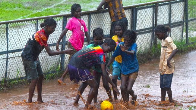 A group of young Tiwi girls playing in the puddles during the second quarter of the men’s game. Picture: Darcy Jennings