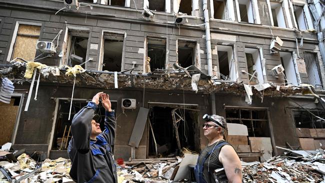 Workers stand in a courtyard amongst debris following an attack on a shopping and office complex in central Kharkiv yesterday (Wednesday) amid the Russian invasion of Ukraine. Picture: AFP