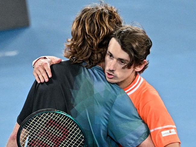 Russia's Andrey Rublev (L) hugs Australia's Alex De Minaur after winning in the men's singles match on day eight of the Australian Open tennis tournament in Melbourne on January 21, 2024. (Photo by Anthony WALLACE / AFP) / -- IMAGE RESTRICTED TO EDITORIAL USE - STRICTLY NO COMMERCIAL USE --