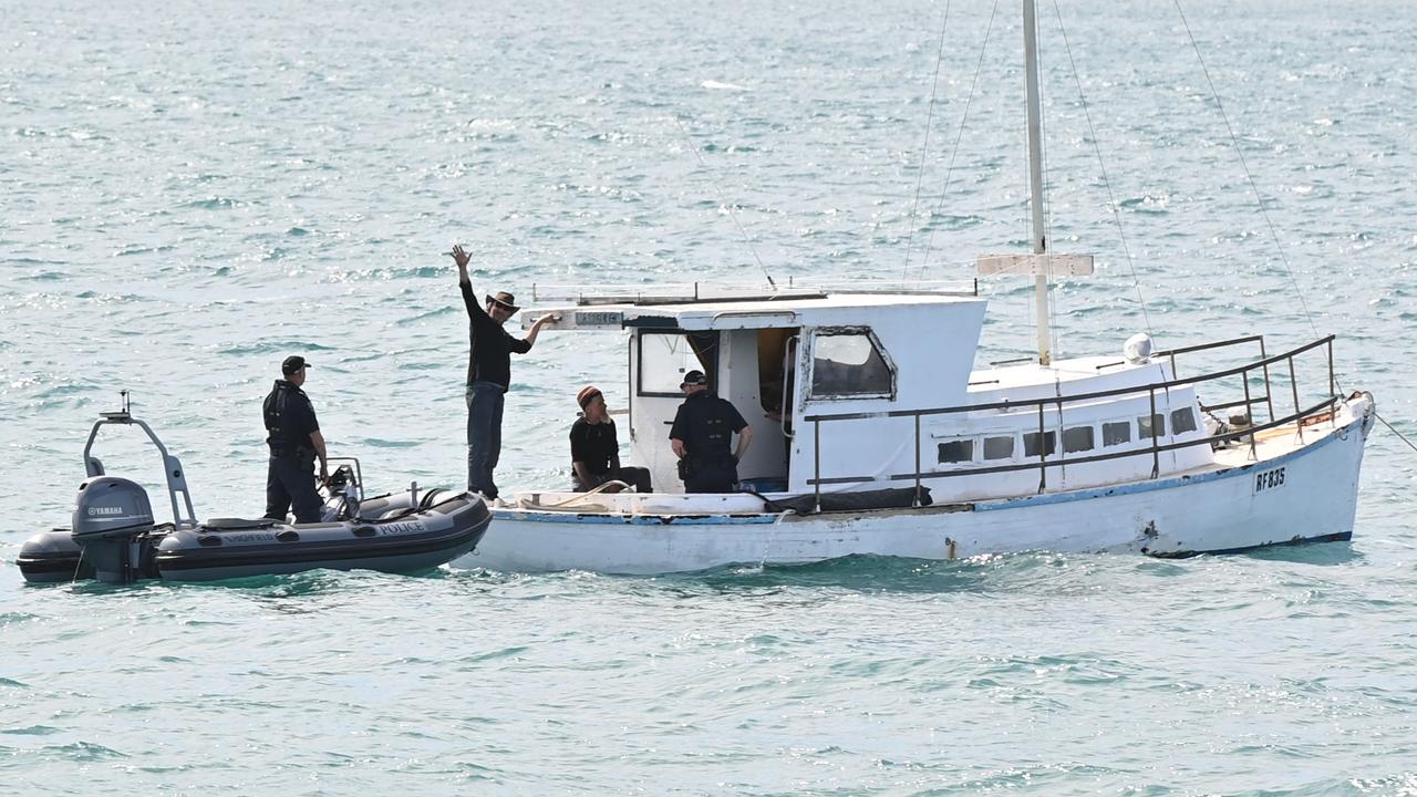 Police pick up the men from their boat in a dinghy. Picture: Keryn Stevens