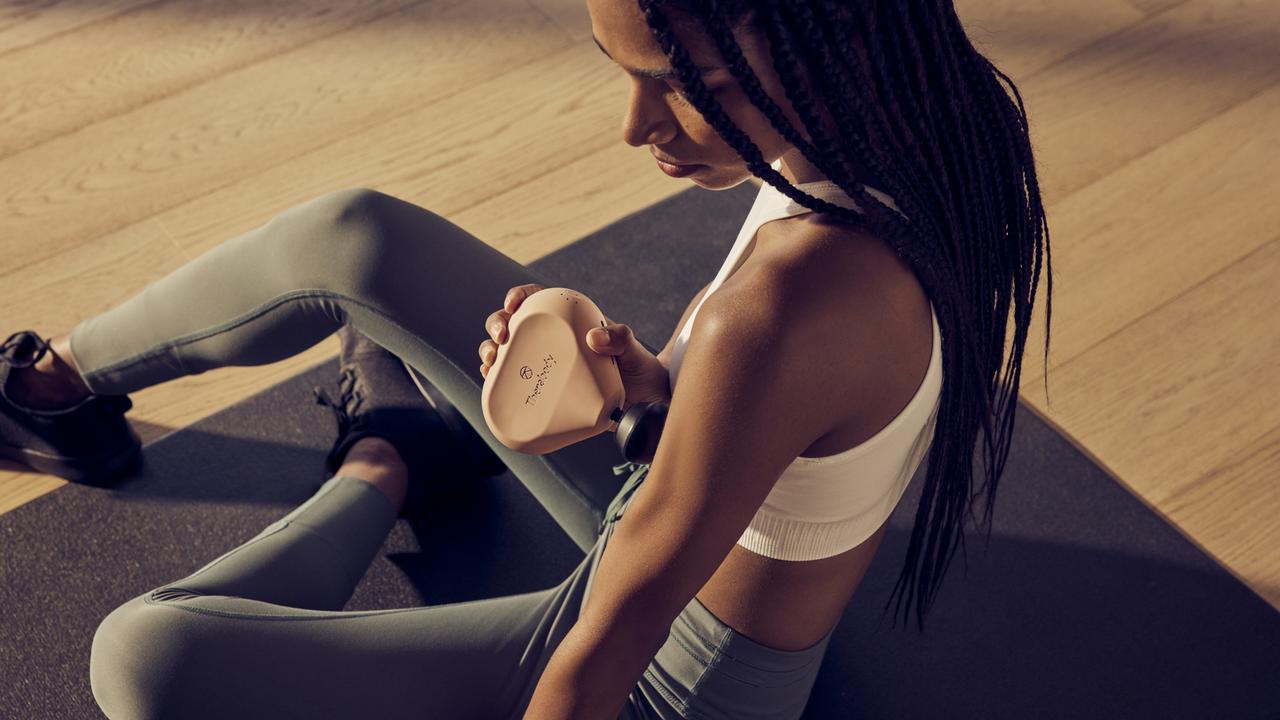 A woman using the Theragun Mini 2.0 in her bicep.