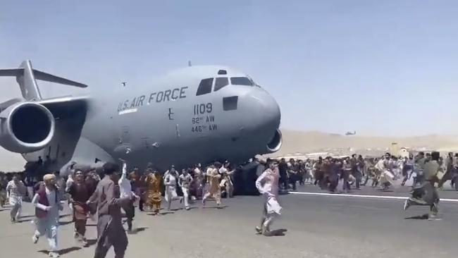 People run alongside a US military aircraft as it attempts to take off from Kabul International Airport.