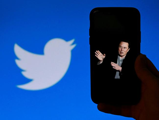 (FILES) In this file illustration photo taken on October 4, 2022, a phone screen displays a photo of Elon Musk with the Twitter logo shown in the background in Washington, DC. - The New York Stock Exchange did not permit trading on Twitter on October 28, 2022 after Elon Musk completed a $44 billion takeover of the social media platform. Twitter was listed among the companies experiencing a "trading halt," according to an NYSE notice that said the merger was "effective." (Photo by OLIVIER DOULIERY / AFP)