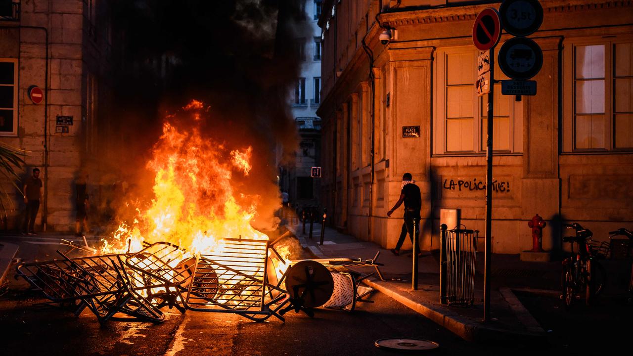 Smoke rises from a bonfire near a graffiti reading "The police kills" during clashes with police in the streets of France. (Photo by JEFF PACHOUD / AFP)