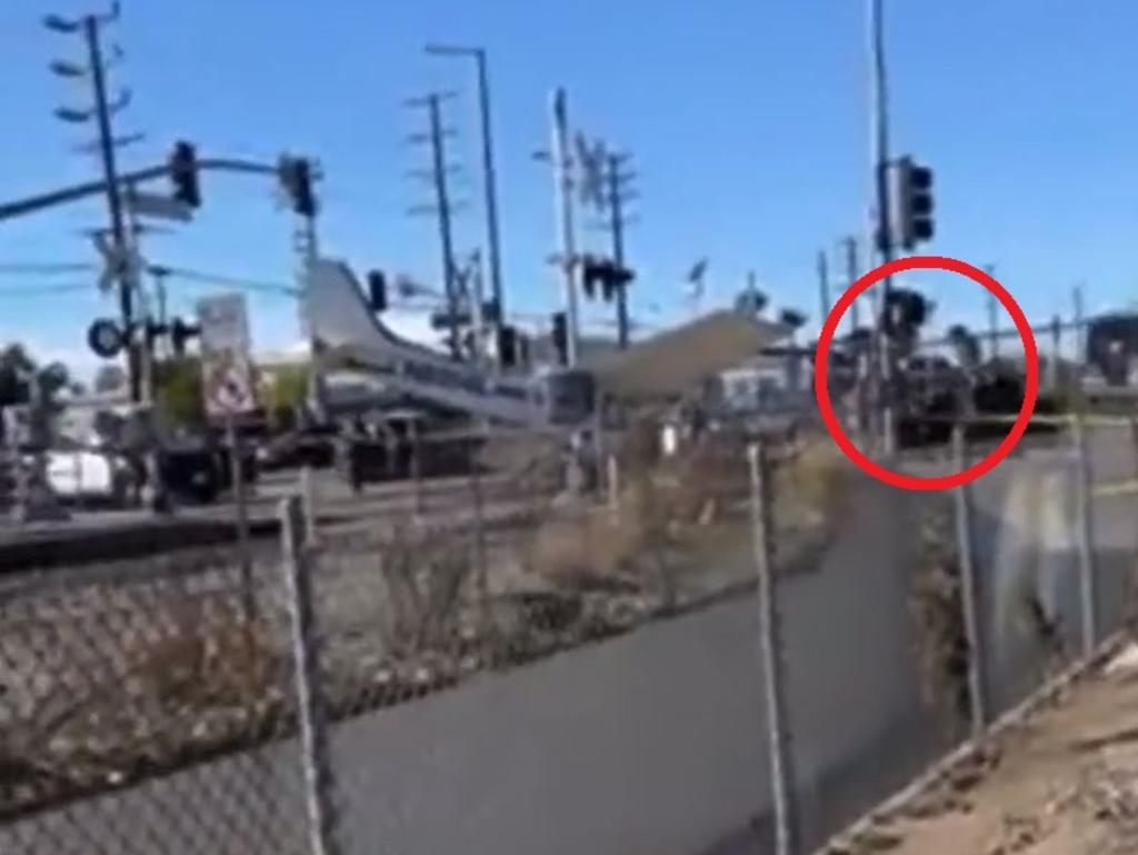 A group rescues the pilot (circled) as the train approaches the stricken plane. Picture: CBS/Luis Jimenez/Twitter