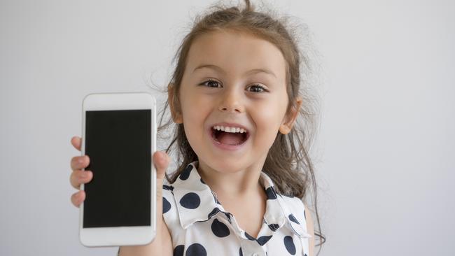 Cute little girl showing mobile phone screen, studio shot. Children with smartphones generic