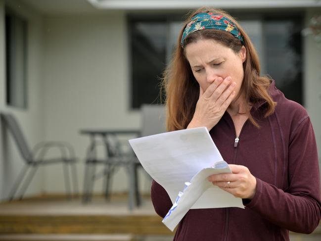 An upset adult woman (female age 25-35) reading a letter in home front yard.bill shock, woman shocked generic money