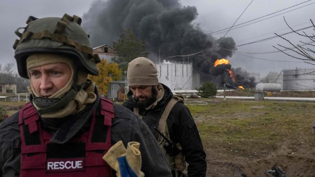 A Ukrainian rescue service member and a soldier inspect the area as black smoke rises from an oil reserve in Kherson. Picture: AFP.