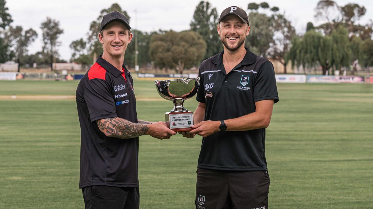 West Adelaide's Hamish Hartlett and Port Adelaide's Cam Sutcliffe holding the Russell Ebert Tribute Match trophy. Picture: Jessica Green