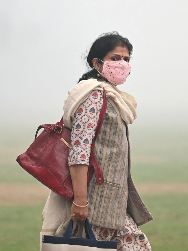 A woman wearing a mask walks along a roadside on a cold smoggy morning in New Delhi. Picture: Money Sharma/AFP