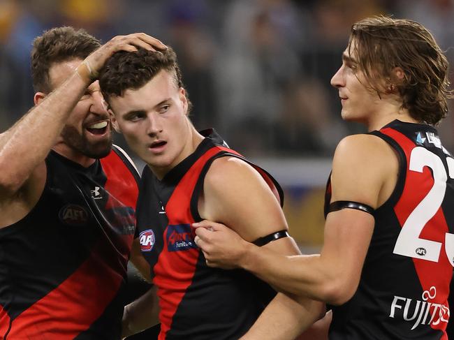 PERTH, AUSTRALIA - MAY 29: Nikolas Cox of the Bombers celebrates a goal with Cale Hooker and Harrison Jones during the round 11 AFL match between the West Coast Eagles and the Essendon Bombers at Optus Stadium on May 29, 2021 in Perth, Australia. (Photo by Paul Kane/Getty Images)