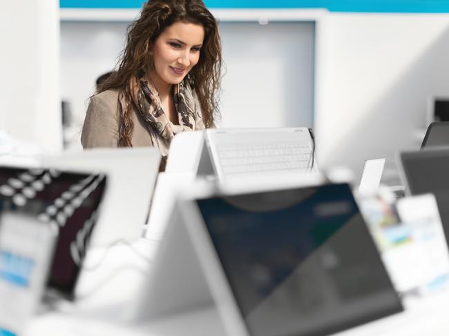 Woman choosing new laptop in electronics store