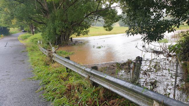 Binna Burra Road as floodwaters lap the roadside.