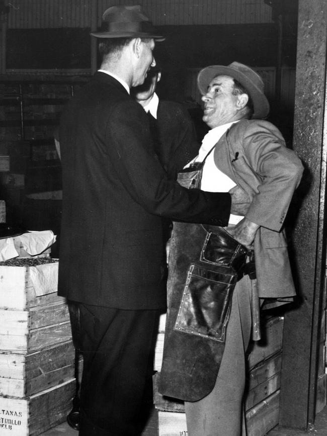 Police frisk a stallholder during the Queen Victoria Market murders. Picture: HWT Library