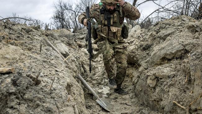 Ukrainian medic runs through a partially dug trench along the frontline outside of Bakhmut, Ukraine. Picture: John Moore/Getty Images