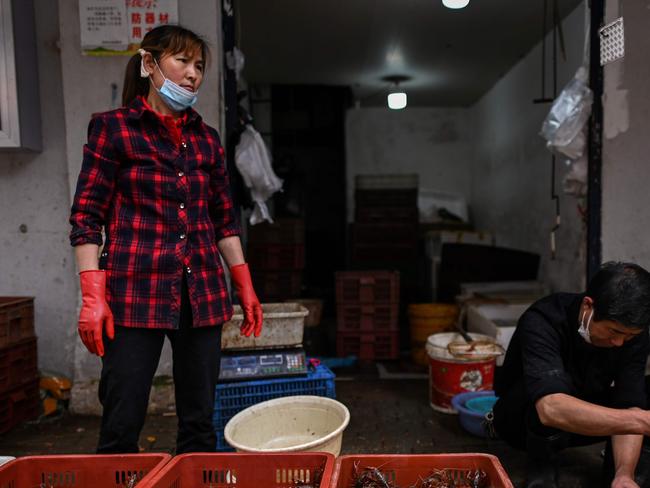 Vendors wearing face masks work at their stall in a market in Wuhan, in China. Picture: AFP