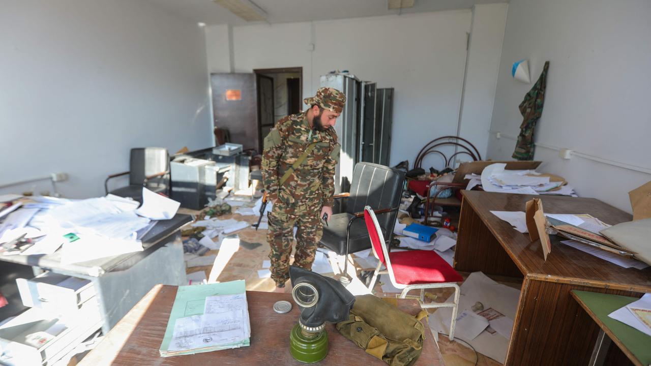 A member of the security forces of Syria's new authorities stands on a pile of papers in a room at the security bureau of the Fourth Division on the outskirts of Damascus. Former division officers reported significant wealth in dollars despite governmental restrictions. Picture: Bakr ALKASEM / AFP