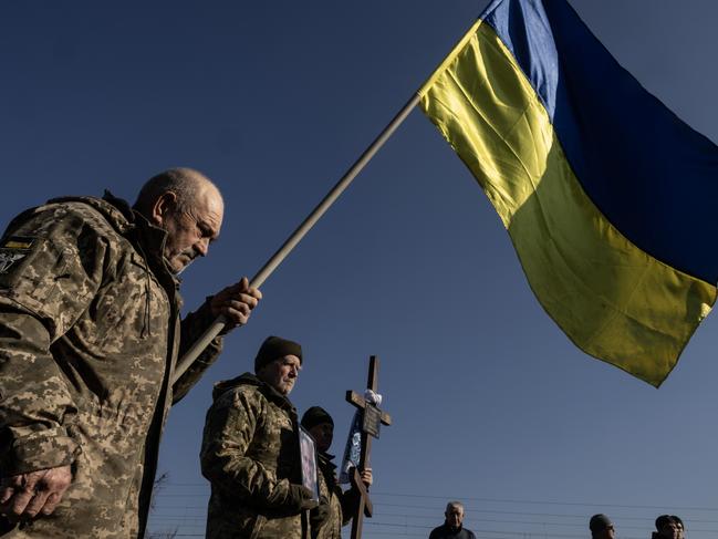 FASTIV, UKRAINE - FEBRUARY 24: A soldier holds a flag during the joint military funerals for Volodymyr Semenyuk, 43, and his military comrade Serhiy Voytenko, 53, on February 24, 2025 in Fastiv, Ukraine. Both soldiers were with the 47th brigade, killed together on February 18th in Kursk (Russia) when a glide bomb hit their position. Monday marks three years since Russia launched a full-scale invasion of Ukraine, with Russian forces continuing to make slow but steady gains across Ukraine's eastern front, while Ukrainian forces have staged a counter-offensive into Russian territory. The milestone comes as tensions between Ukraine and its key ally, the United States, have been escalating since  Ukraine was excluded last week from bilateral talks between American and Russian diplomats, on laying the groundwork for peace negotiations. (Photo by Paula Bronstein/Getty Images)