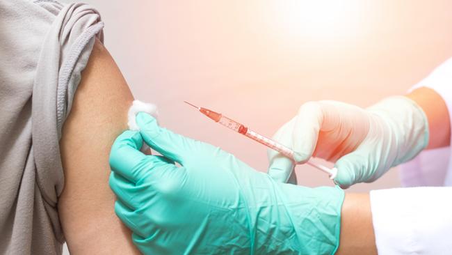 Vaccination healthcare concept. Hands of doctor or nurse in medical gloves injecting a shot of vaccine to a man patient