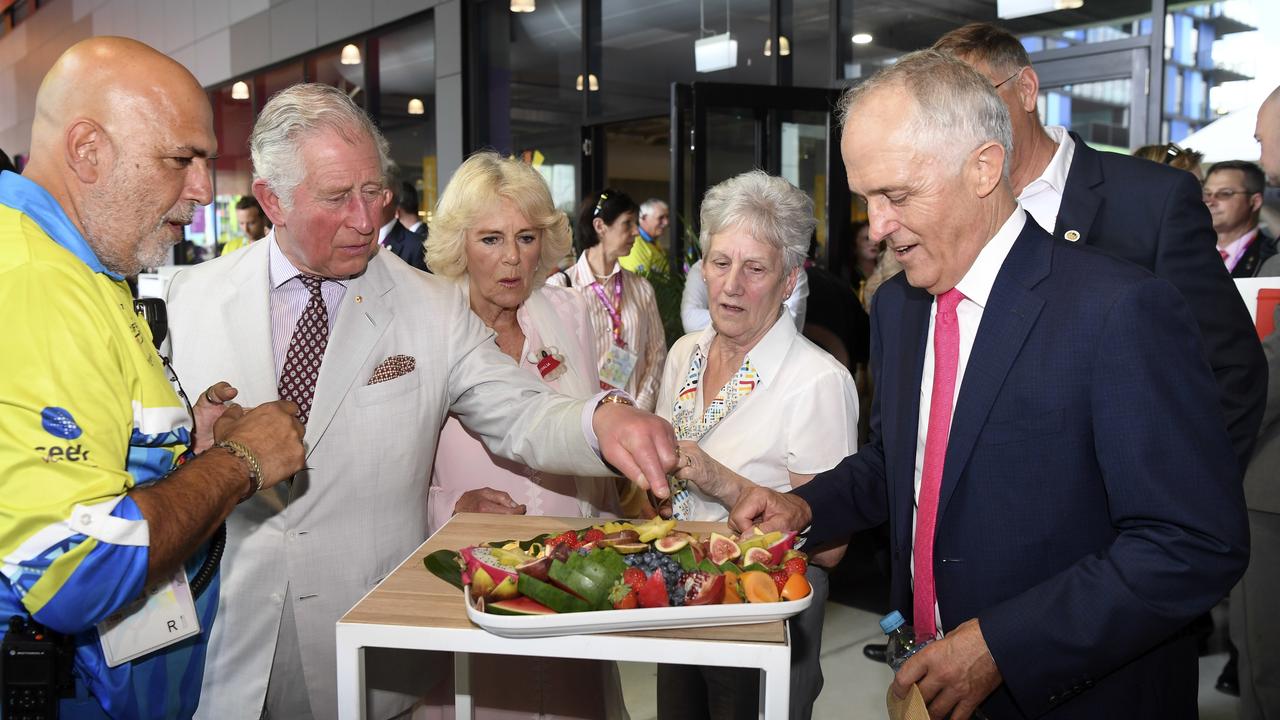 Prince Charles, Prince of Wales (second left) and Camilla, Duchess of Cornwall (centre) taste fruit available to athletes with Australian Prime Minister Malcolm Turnbull (right) during a visit to the Athlete's Village on the Gold Coast, Thursday, April 5, 2018. (AAP Image/AFP Pool/William West)