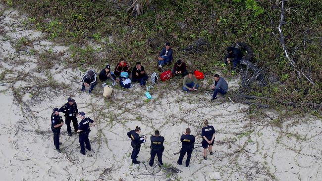 Police and Boarder Force officers guard some of the men. Picture: Marc McCormack