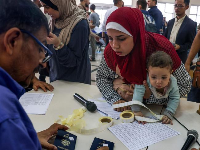 Civilians leaving display their documents as dual national Palestinians and foreigners prepare to cross the Rafah border point with Egypt, in the southern Gaza Strip. Picture: AFP