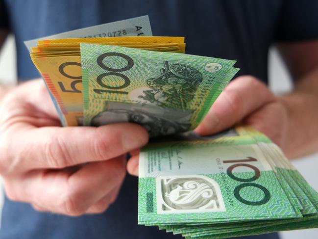 A man counting Australian dollar bills. A picture that describes buying, paying, handing out money, or showing money. Australian cash money generic