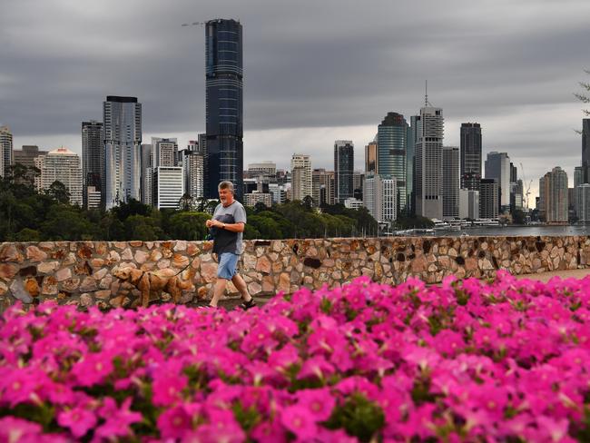 A man is seen walking his dog at the Kangaroo Point cliffs as storm clouds gather over the Brisbane CBD on Friday, March 15, 2019. South-East Queensland has had a record-breaking March heatwave with Brisbane peaking at 37.7C on March the 12th, its hottest March day since 2007. (AAP Image/Darren England) NO ARCHIVING