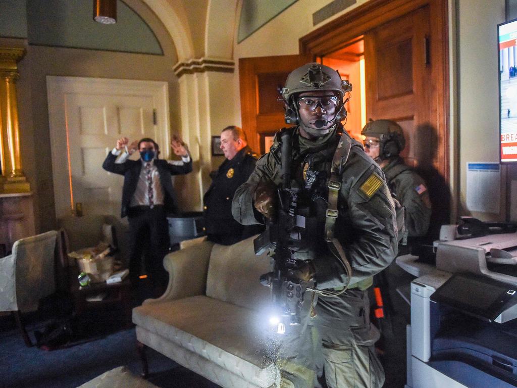 A Congress staffer holds his hands up while Capitol Police Swat team check everyone in the room as they secure the floor of Trump supporters in Washington. Picture: Olivier DOULIERY / AFP