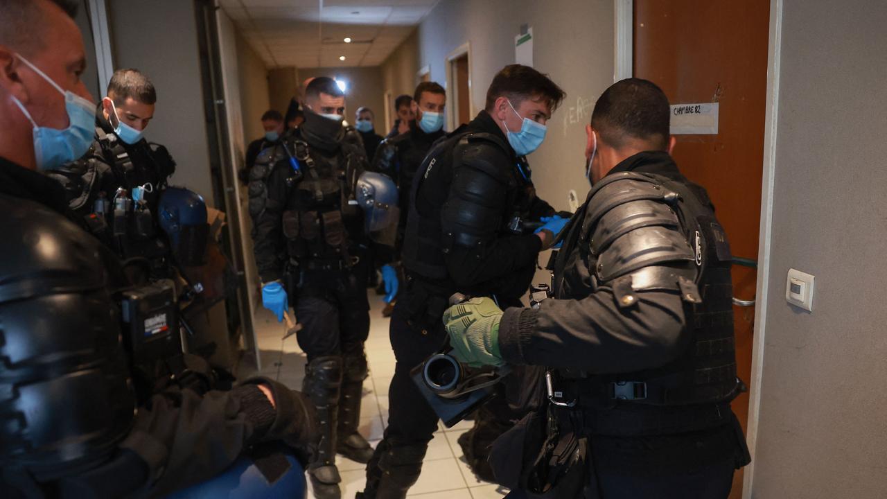 French gendarmes force an entrance door to get migrants to leave. The operation, which had been expected for several days, prompted many of the homeless who had taken refuge in this disused factory in Vitry-sur-Seine to leave before the arrival of the large numbers of police. Picture: Emmanuel Dunand / AFP