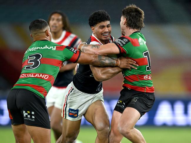 Robert Toia (centre) is tackled by Latrell Mitchell (left) in round five.