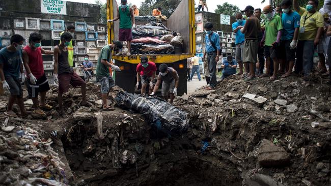 Workers burying cadavers in various stages of decomposition in a mass grave in Manila, after health officials recovered the cadavers from Henry's Funeral Home. Picture: AFP / Noel Celis.