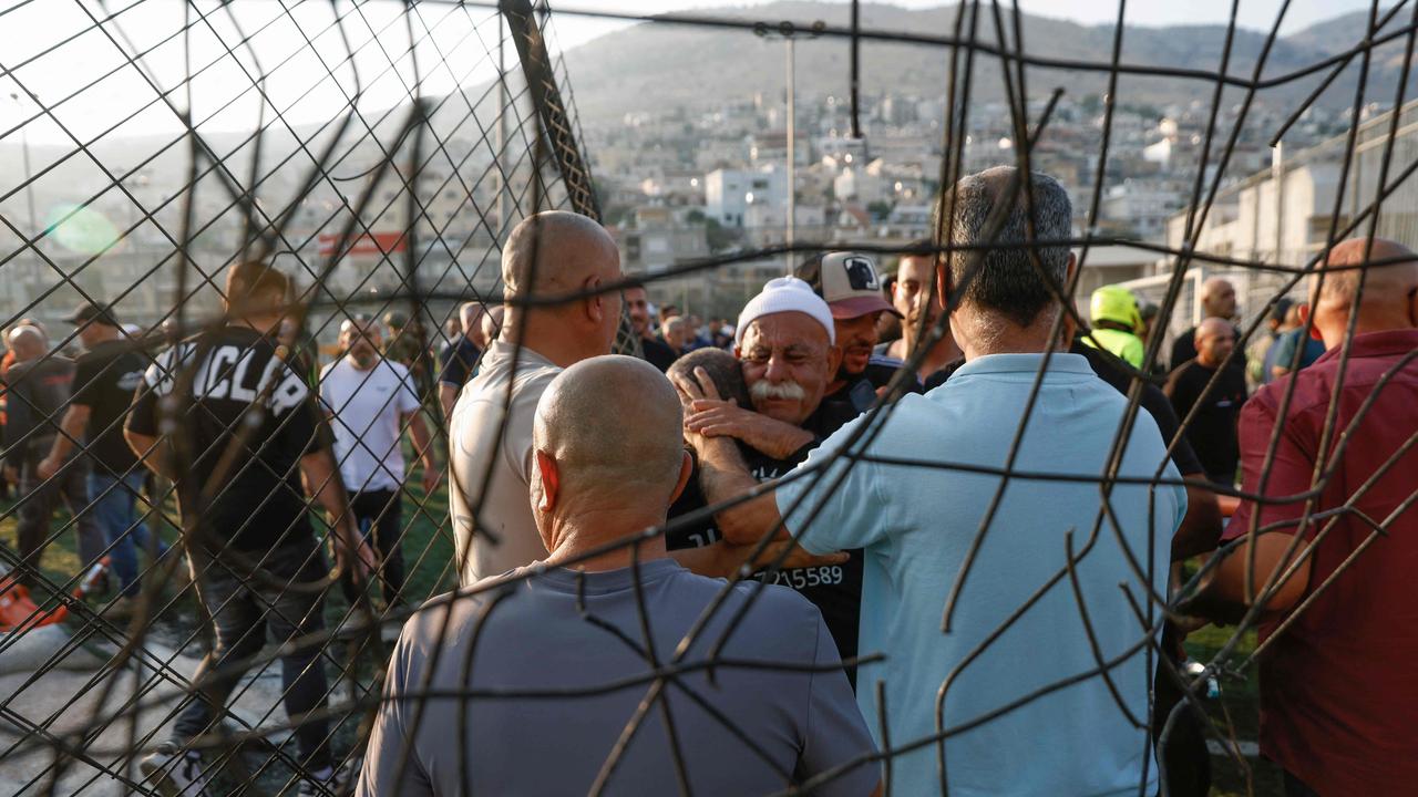 Local residents comfort each other as they gather at a site of a reported strike from Lebanon in Majdal Shams village. Picture: AFP.