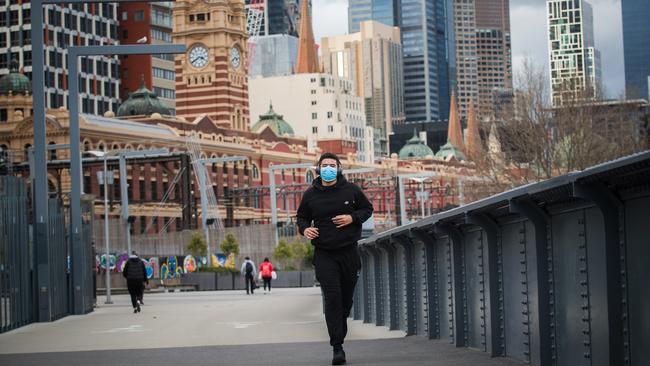 A jogger wearing a face mask runs across Sandridge Bridge in Melbourne’s Southbank on Sunday. Picture: Paul Jeffers